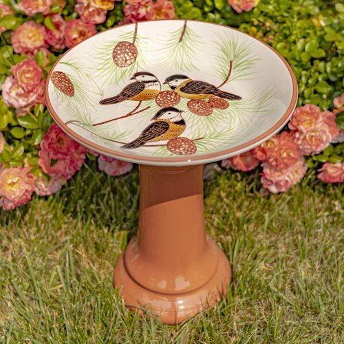 Decorative bird bath with bird design on a grassy background with flowers