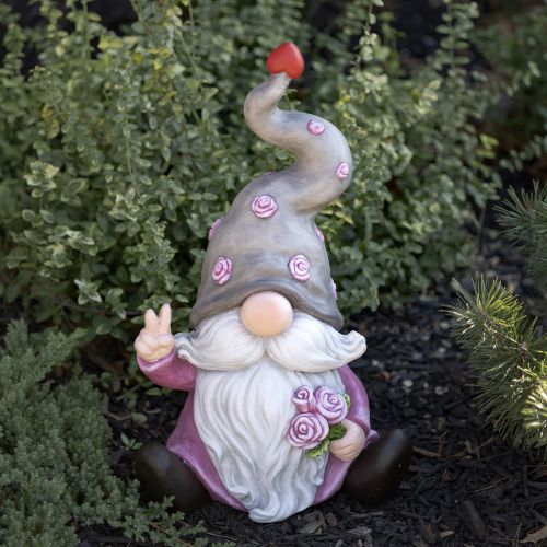 Gnome figurine with a pink outfit and red hat among green plants