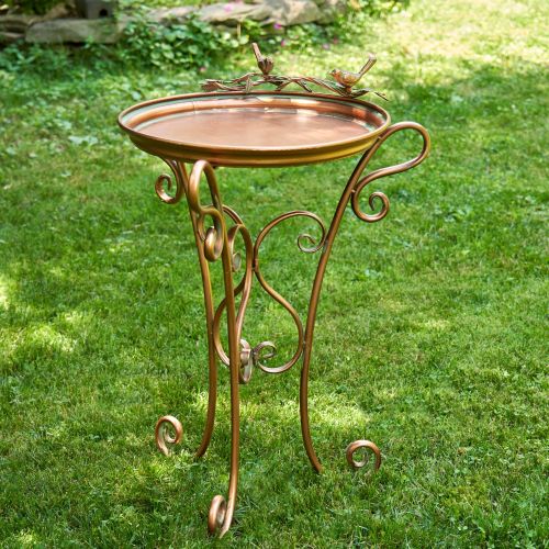 Decorative metal side table with bird design on a grassy background